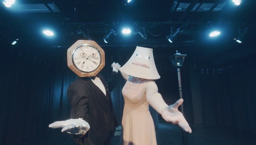 Surreal stage performance with clock and lamp figures